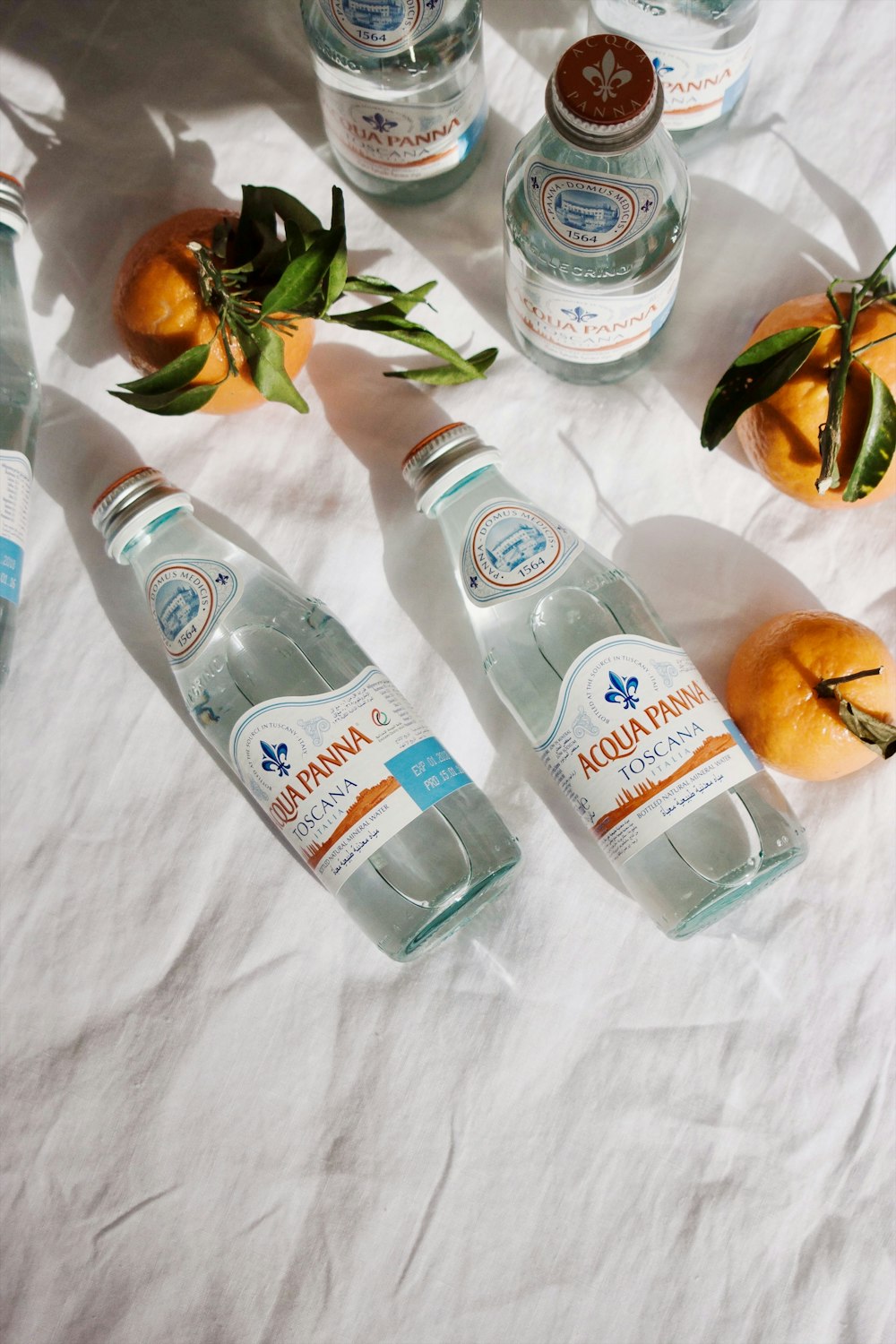 two Acqua Panna bottles beside orange fruits