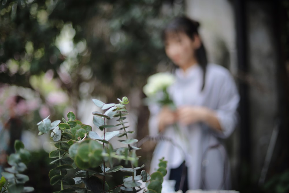 Selektive Fokusfotografie einer Pflanze in der Nähe einer stehenden Frau