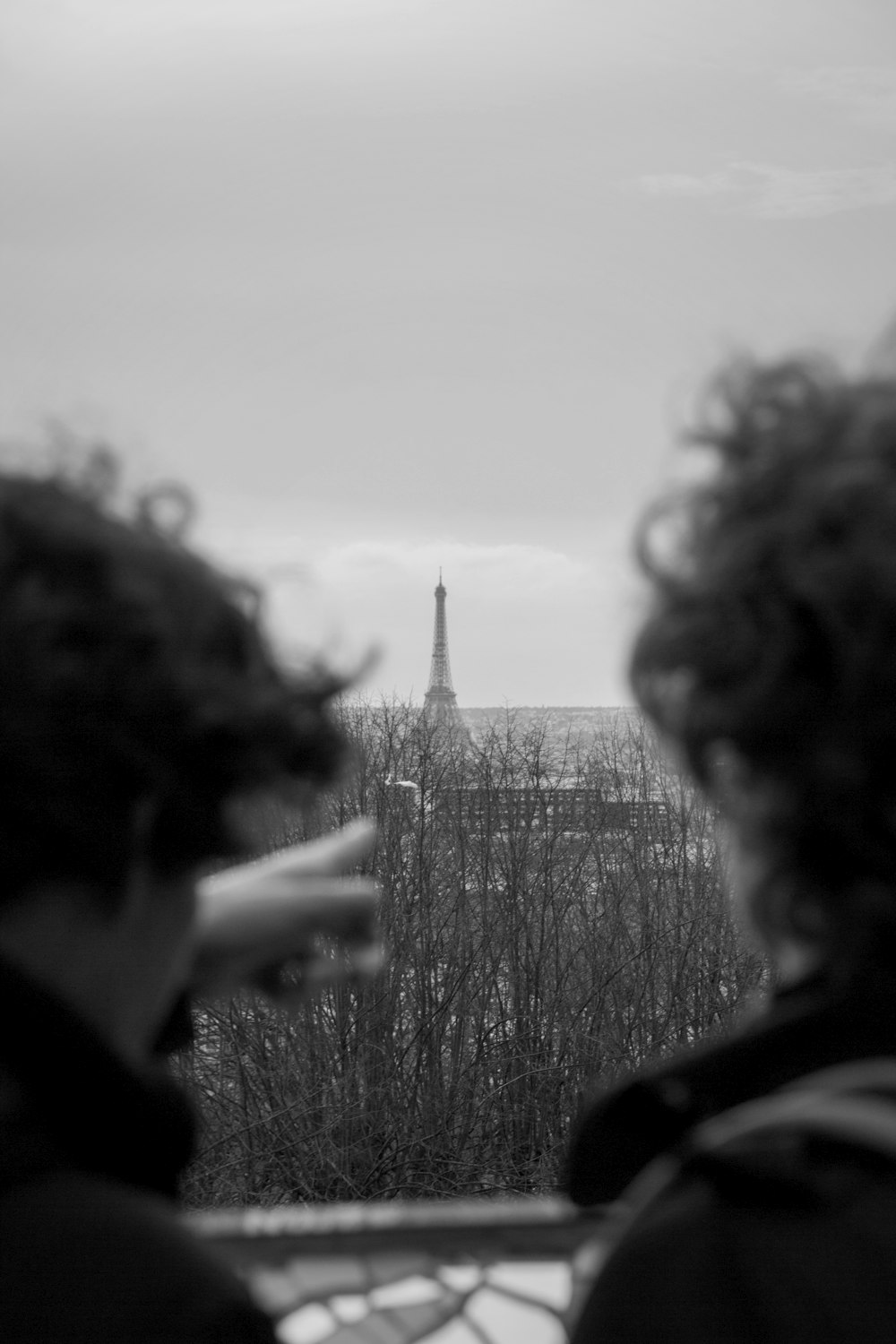 grayscale photo of man pointing at Eiffel tower