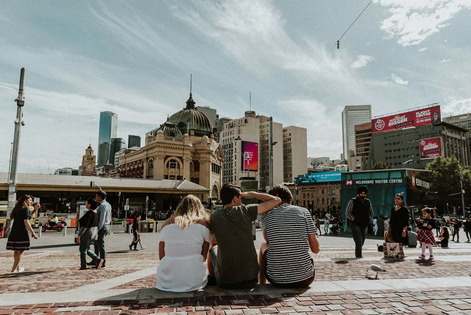 three person sitting on stair in front of building during daytime