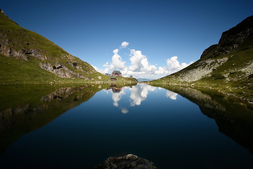 body of water between green grass covered hills