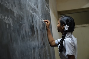woman standing writing on black chalkboard