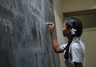 woman standing writing on black chalkboard