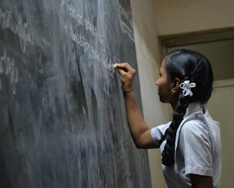 woman standing writing on black chalkboard