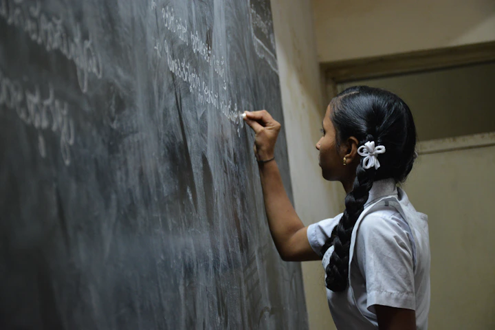 Teacher writing on chalkboard at NewAge PU College