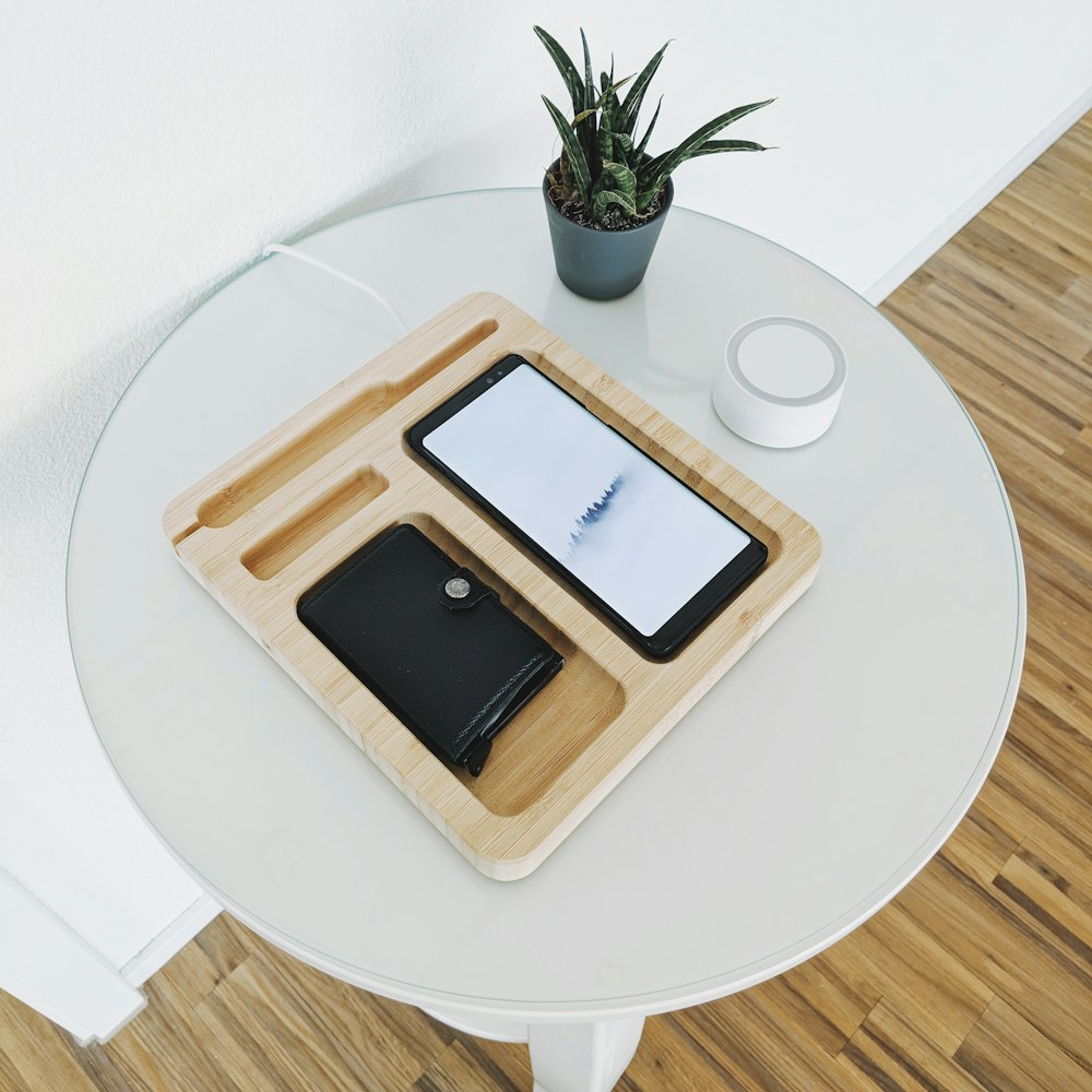 smartphone preto com carteira na bandeja de madeira na mesa