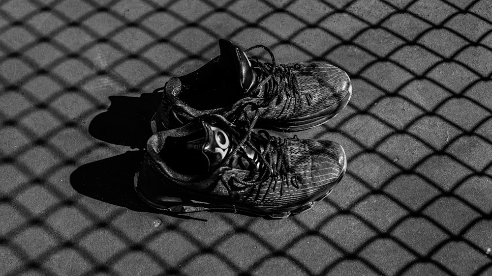 par de sapatos de basquete preto na superfície cinza