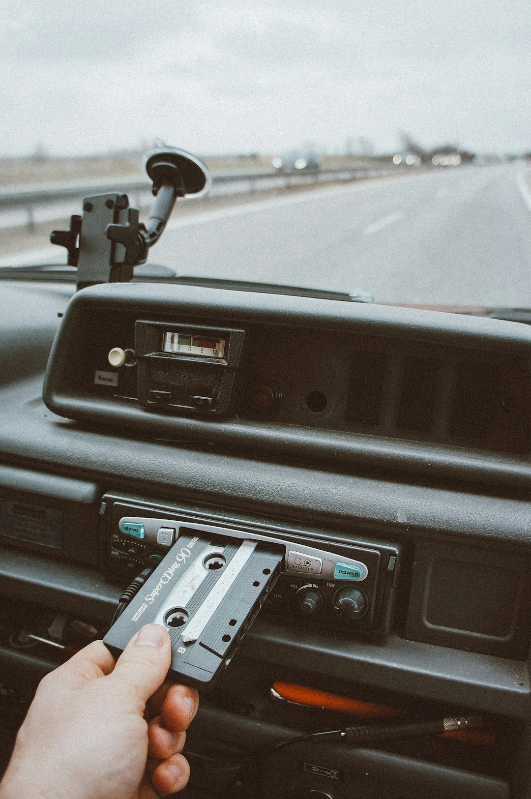 Car's dashboard with cassette player and cassette being inserted.