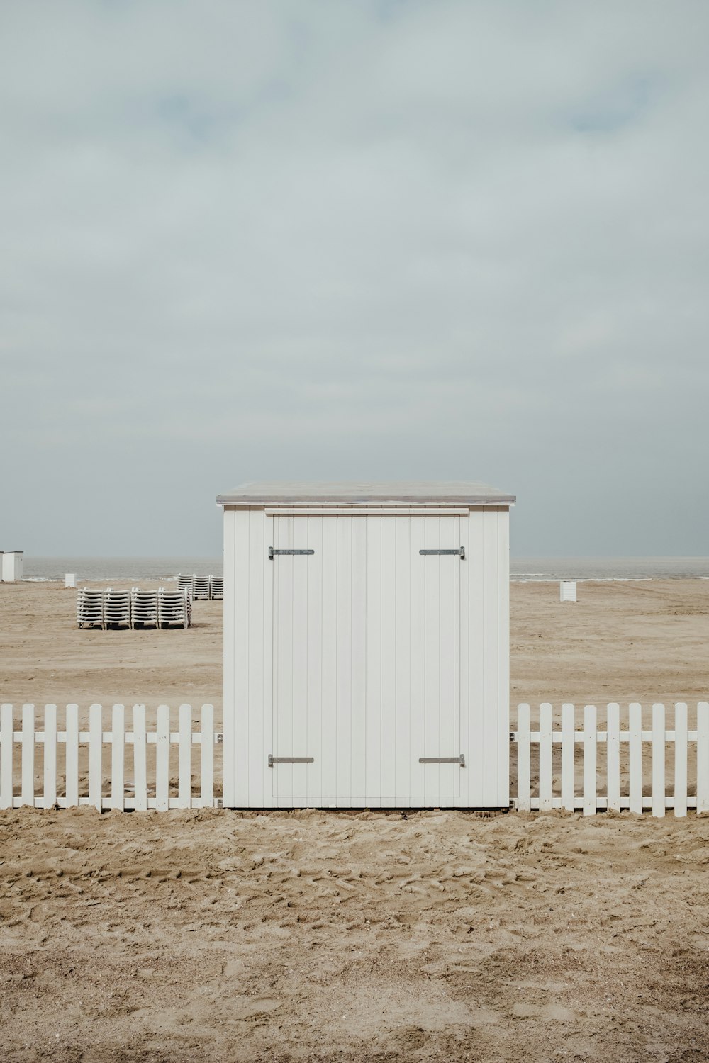 capannone di legno bianco sulla sabbia sotto nuvole bianche