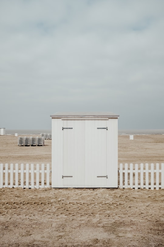 white wooden shed on sand under white clouds in Knokke Belgium