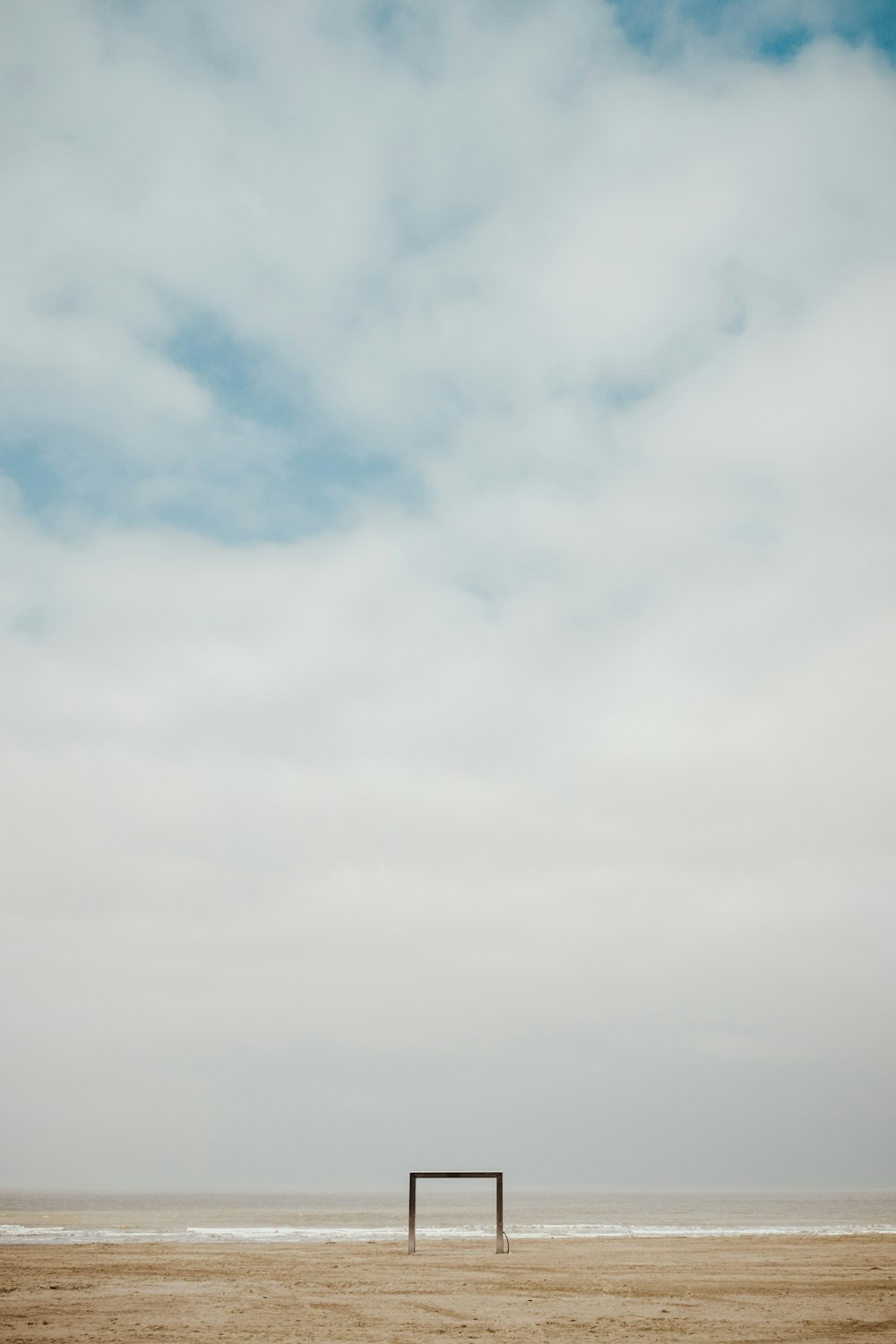 black frame standing on sand under white clouds