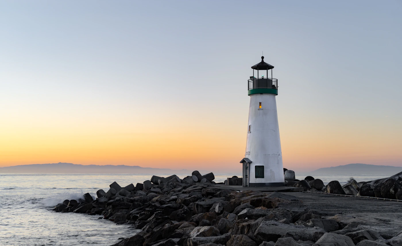 Lighthouse on rocky coastal cliffs at golden hour