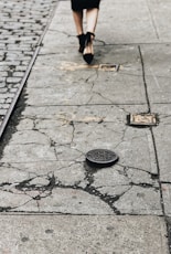 woman in black heeled sandals walking on gray concrete pavement
