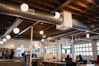 Close-up of industrial style seating area with concrete textures and cozy warm lights in a modern cafe.