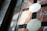 Geometric tiles are arranged in an intricate pattern with octagonal and square shapes made of marble, featuring a combination of white, black, and reddish colors. Sunlight casts shadows across the surface, creating a play of light and shadow that highlights the texture of the materials.