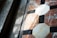 Geometric tiles are arranged in an intricate pattern with octagonal and square shapes made of marble, featuring a combination of white, black, and reddish colors. Sunlight casts shadows across the surface, creating a play of light and shadow that highlights the texture of the materials.