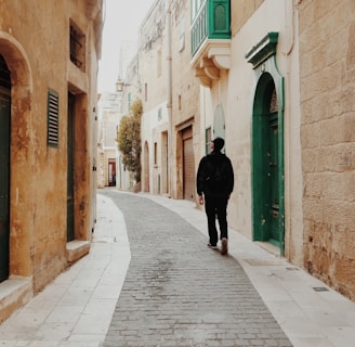 man walking in the middle of the street surrounded by buildings