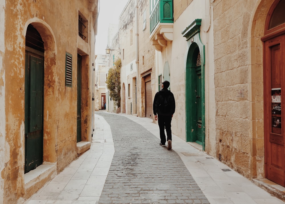 man walking in the middle of the street surrounded by buildings