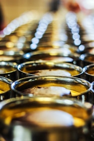 Close-up of shiny tin cans lined up on a factory conveyor belt under bright lights.
