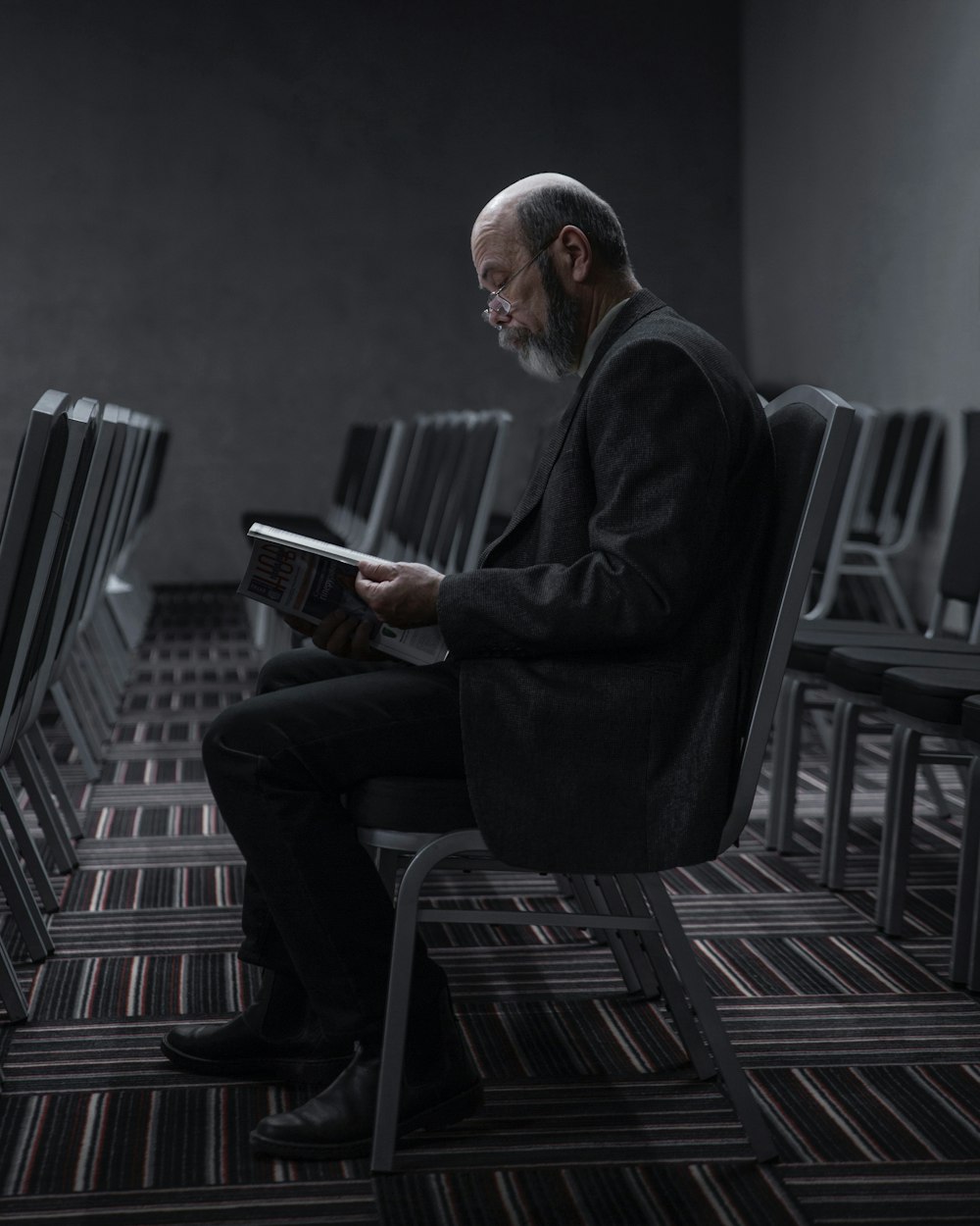 homme en costume noir assis sur une chaise