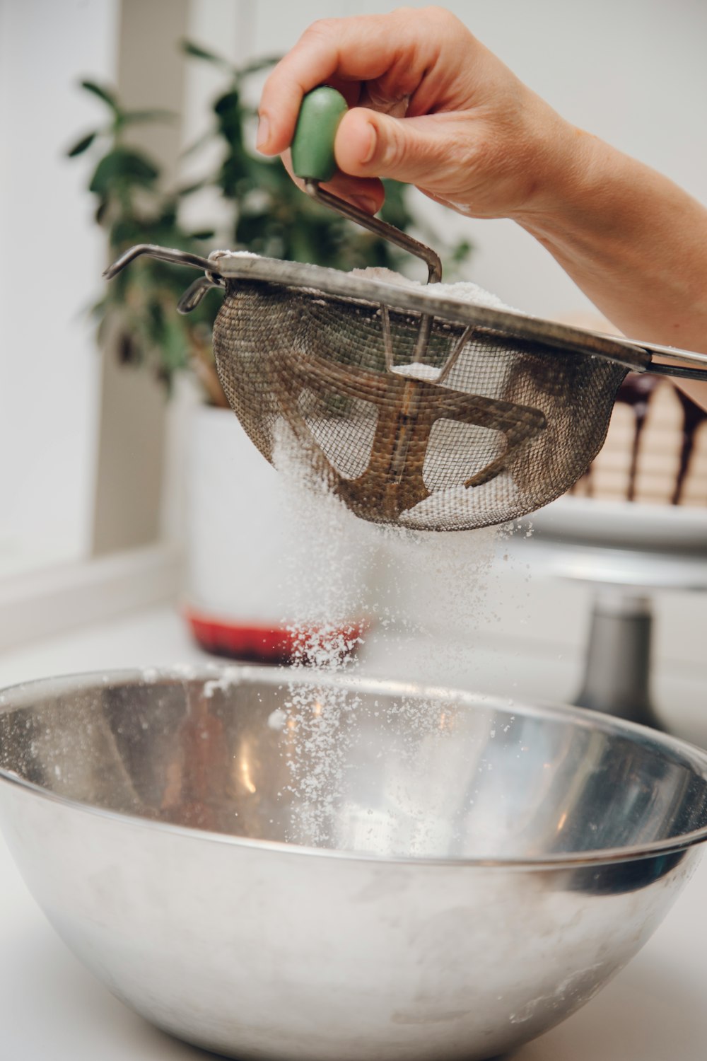 person filtering powder on round stainless steel bowl