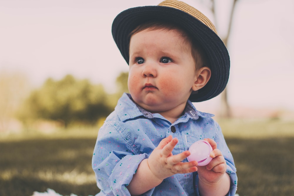 niño pequeño sosteniendo la pelota mientras está sentado