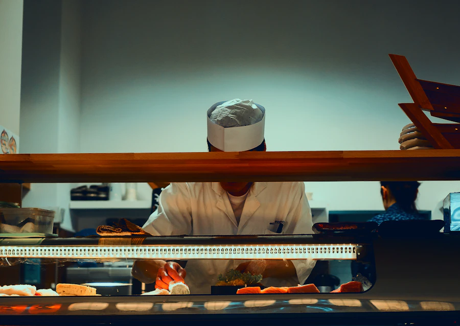 Itamae in a white jacket working quietly behind a hinoki sushi counter