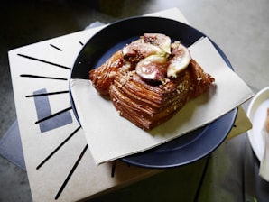 Close-up of a golden, flaky feteer topped with honey and crushed nuts on a rustic wooden board.
