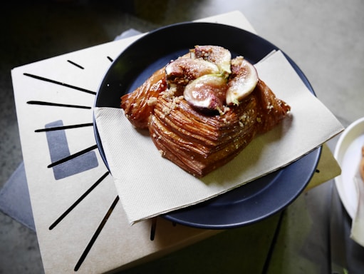Close-up of a golden, flaky feteer topped with honey and crushed nuts on a rustic wooden board.