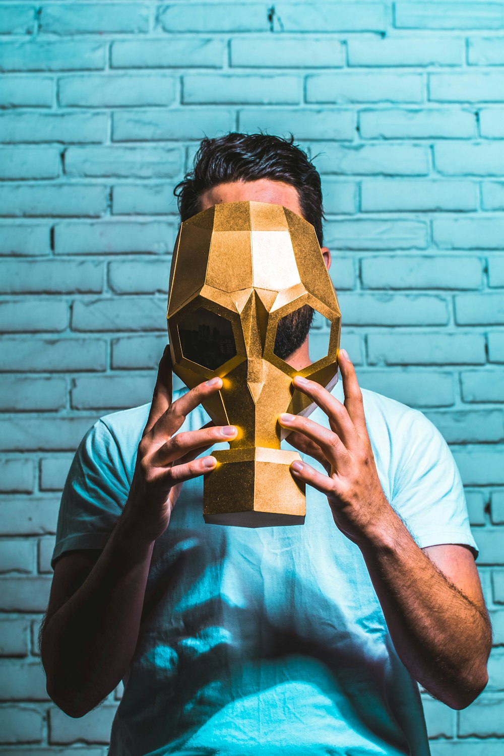 homem segurando uma máscara com tinta dourada