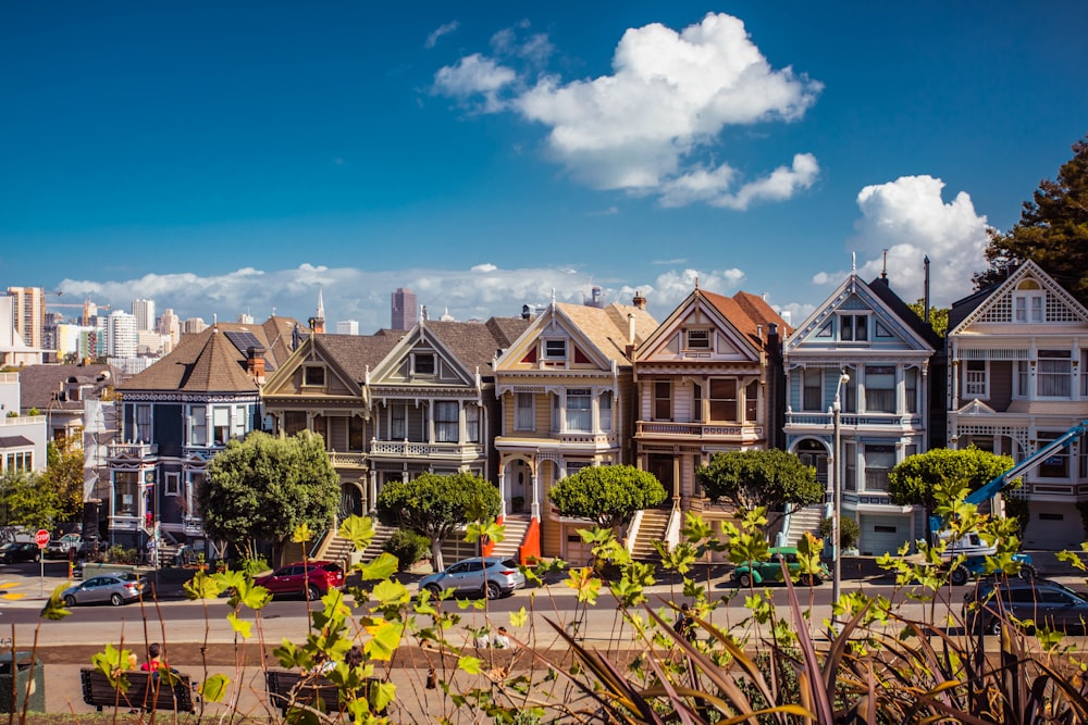 white and brown 2-storey houses with vehicles in front during daytime