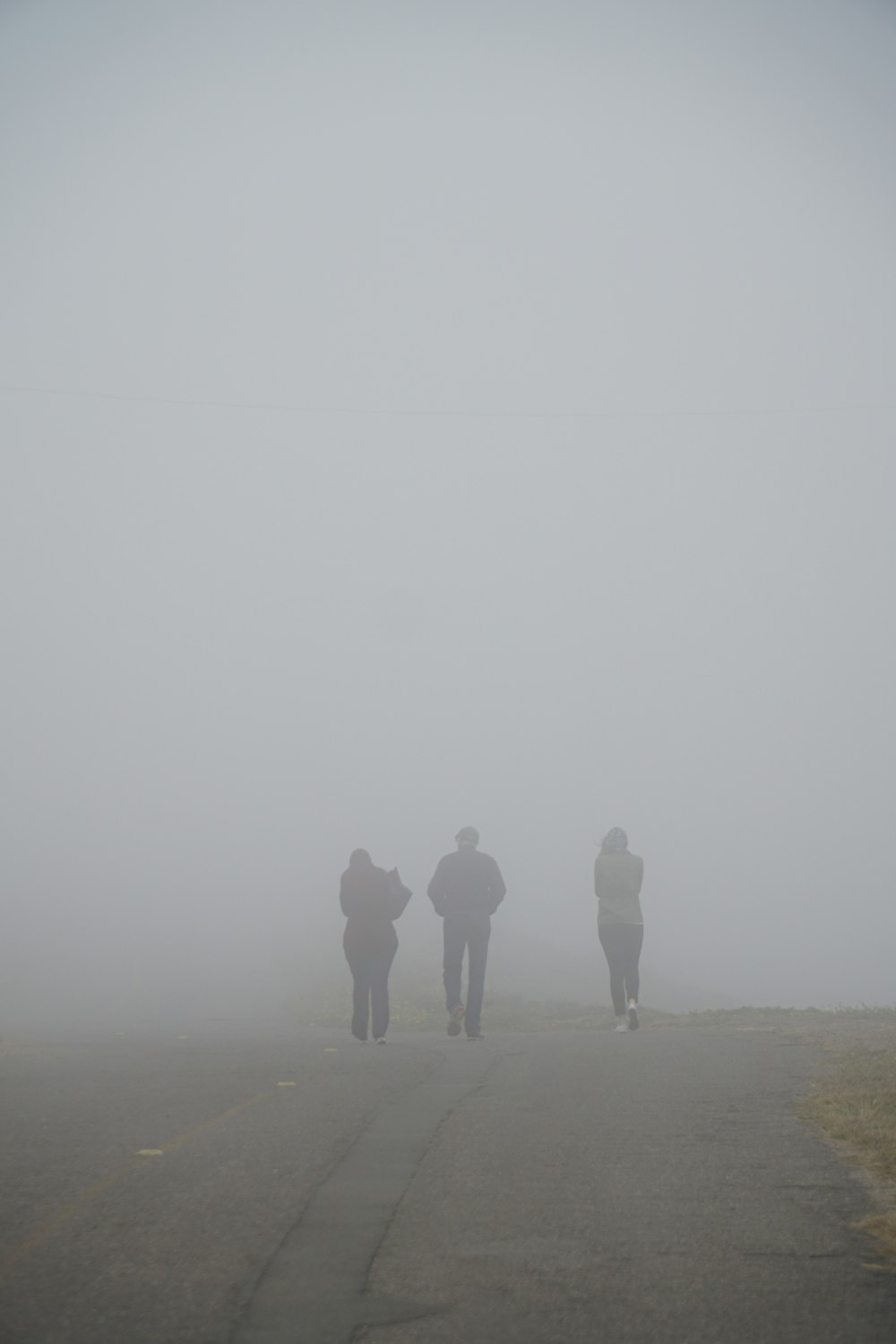 three people walking on dirt trail