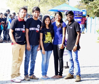 A group of people wearing matching event t-shirts outdoors, smiling and interacting.