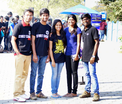 A group of smiling teenagers holding copies of the mental health awareness magazine outdoors.