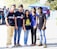 A diverse group of young adults happily showcasing fashionable clothing outdoors.