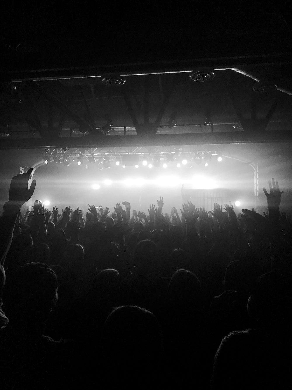 grayscale photo of people raising hands