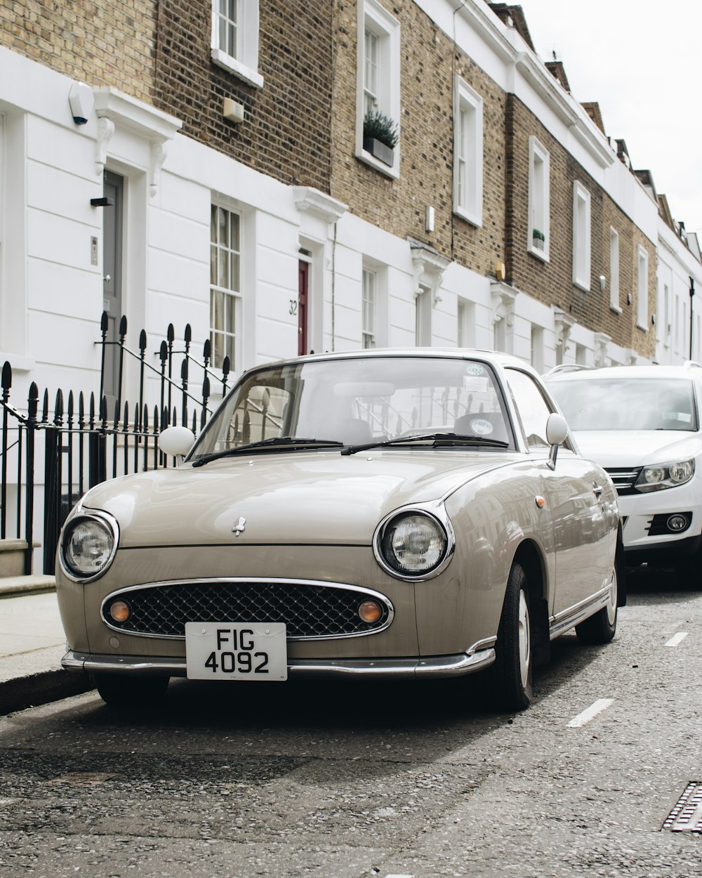 brown car on street beside white and brown concrete houses