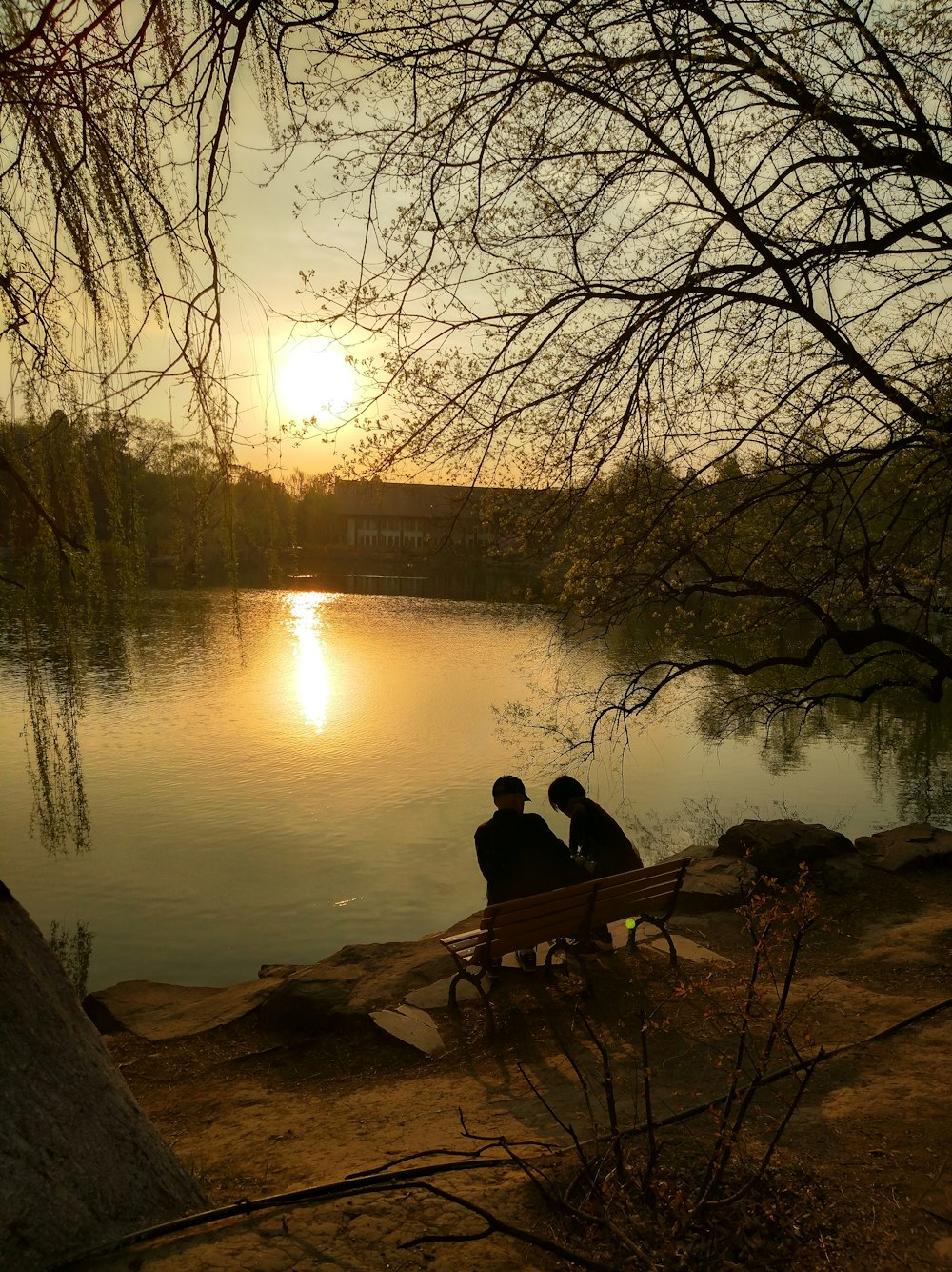 two person sitting on bench near lake