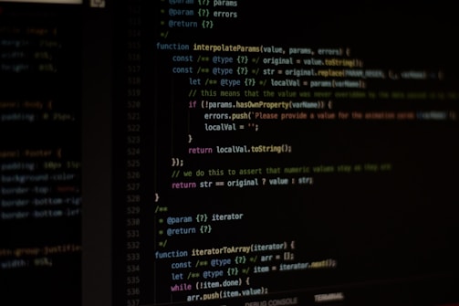 A professional workspace with a computer displaying code on a dark-themed screen.
