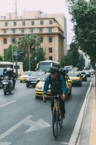 man riding bicycle on a road with cars during daytime