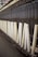 A row of large, vertical spinning spindles, likely part of a textile or yarn production machine. The spindles are light-colored and arranged neatly along a metal framework.