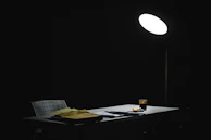 A cozy desk scene with a pen, paper, and a softly glowing lamp casting warm yellow light.
