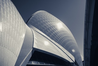 Distinctive architectural design featuring curved, sail-like structures with a textured, tiled surface that reflects light.