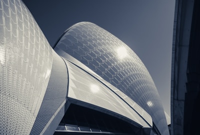 Distinctive architectural design featuring curved, sail-like structures with a textured, tiled surface that reflects light.