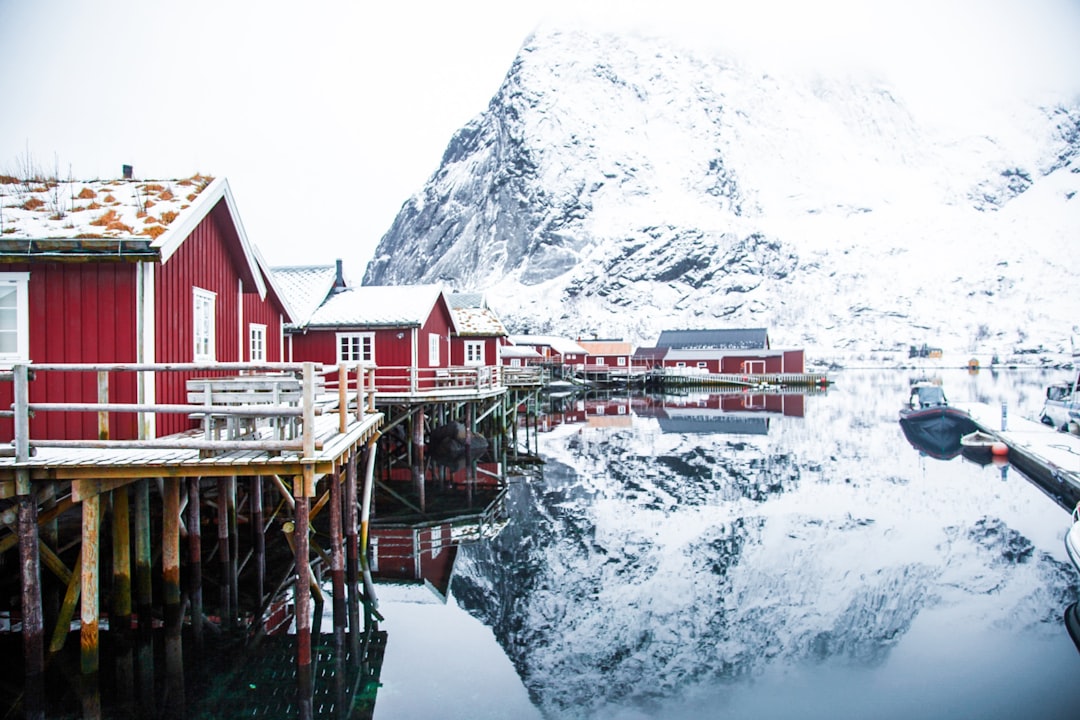 house on body of water near mountain alps, Shot on a tripe to lofoten with 3 friends - wondering through the village of 
