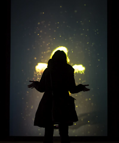 A cinematic high-definition image of a silhouetted figure standing before a glowing portal, with swirling smoke and celestial light beams piercing through dark clouds.