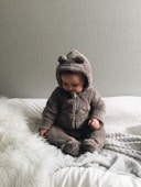 baby seating on white textile