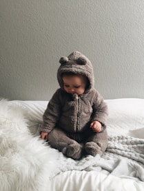 baby seating on white textile