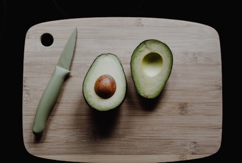 sliced avocados on top of brown wooden chopping board in top view photography