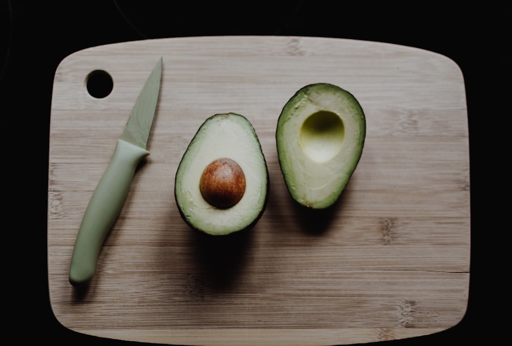 sliced avocados on top of brown wooden chopping board in top view photography